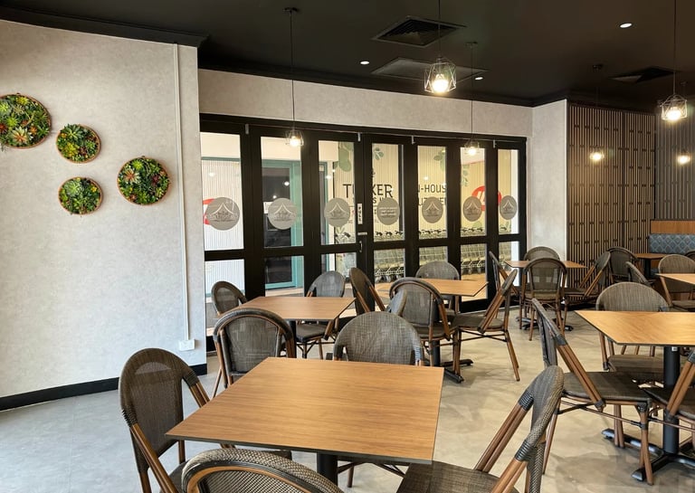 Modern cafe interior with wooden tables, woven chairs, and decorative wall succulents.