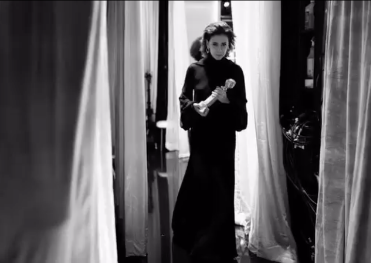a woman in a black dress standing in front of a door