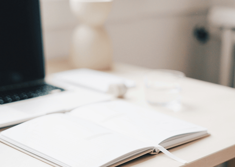 Escritorio con portátil, libreta abierta en oficina luminosa, ideal para contable freelance