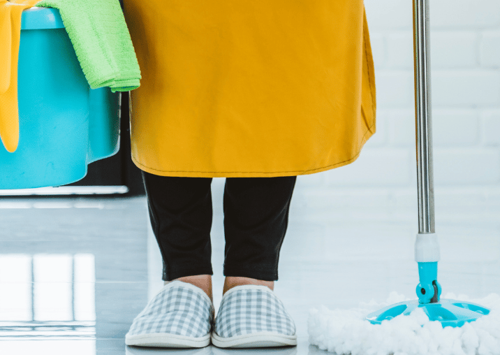 a woman in a yellow dress holding a mop and cleaning supplies