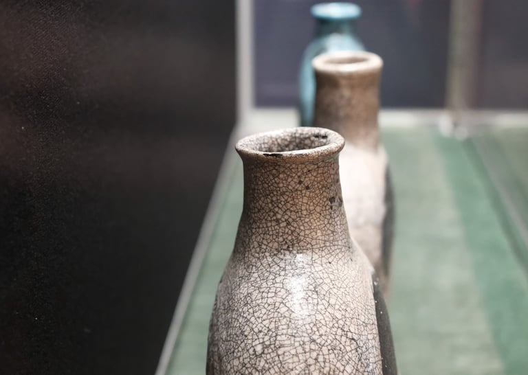 3 ceramic vessels in a row, shaped as historic 'pilgrim flasks' with pale pink raku glaze