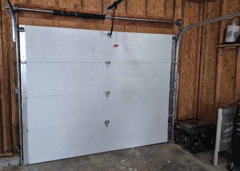 Interior view of a modern white sectional garage door installation with overhead tracks and spring system.