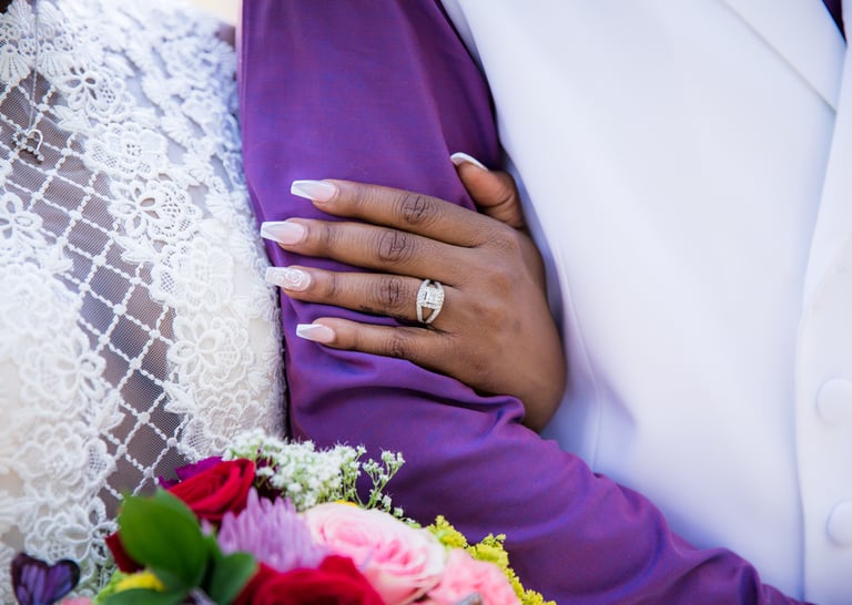 bride holding grooms arm brides wedding band and bouquet 