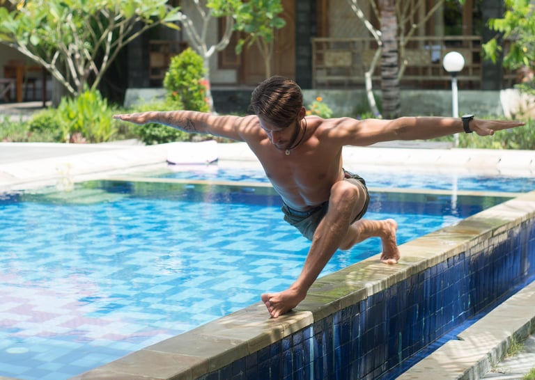 a man is doing a yoga pose on a pool side