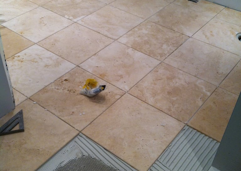Close-up of a craftsman carefully laying marble tiles on a floor.