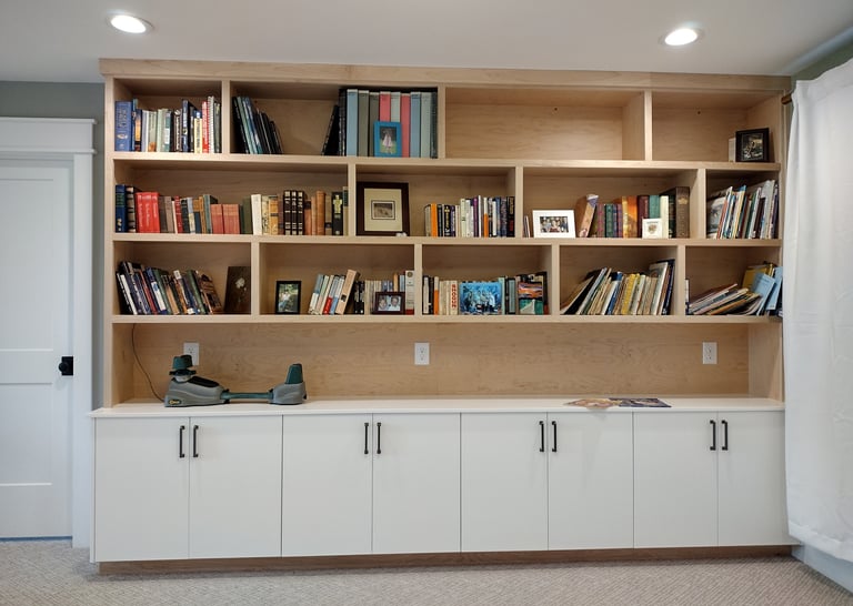 Custom built-in wooden bookshelves and white storage cabinets for home office organization.