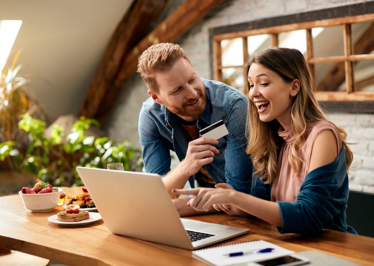a man and woman are looking at a laptop and credit card