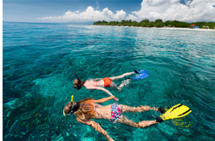 two people are swimming in the ocean with a yellow life jacket