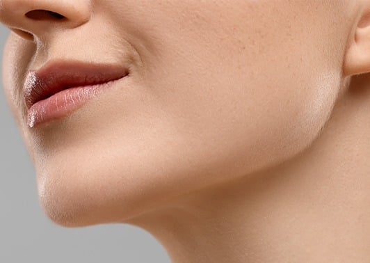 Close-up of a woman's lower face, showing a defined jawline and neck.