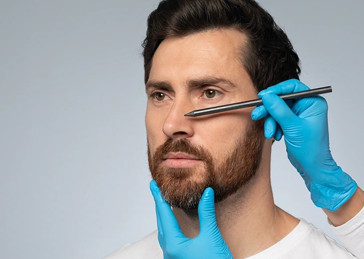 Wireframe nose on man's face, gloved hand touches, symbolizing surgical planning.