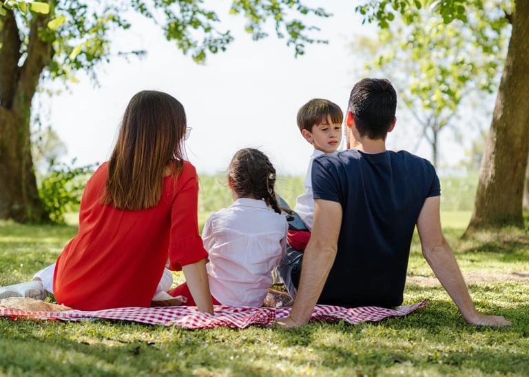 Eine Familie mit zwei Kindern sitzt beim Picknick.