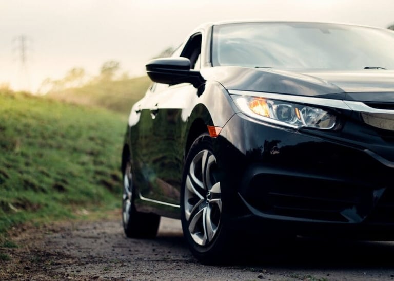 a black car parked on a dirt road