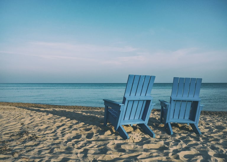 two beach chairs facing the water