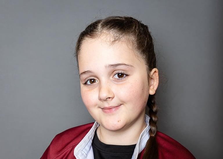 a girl with a ponytail in a rugby tshirt  is smiling towards the camera
