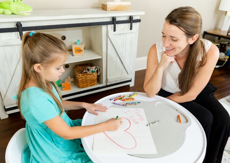 A therapist and child working on an art project titled "things I love.." 