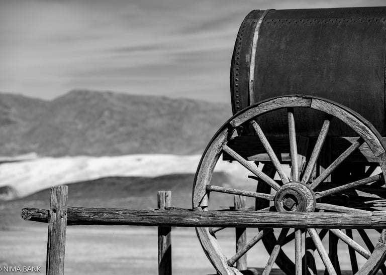 black and white wooden wagon with mountains in background in death valley califormia