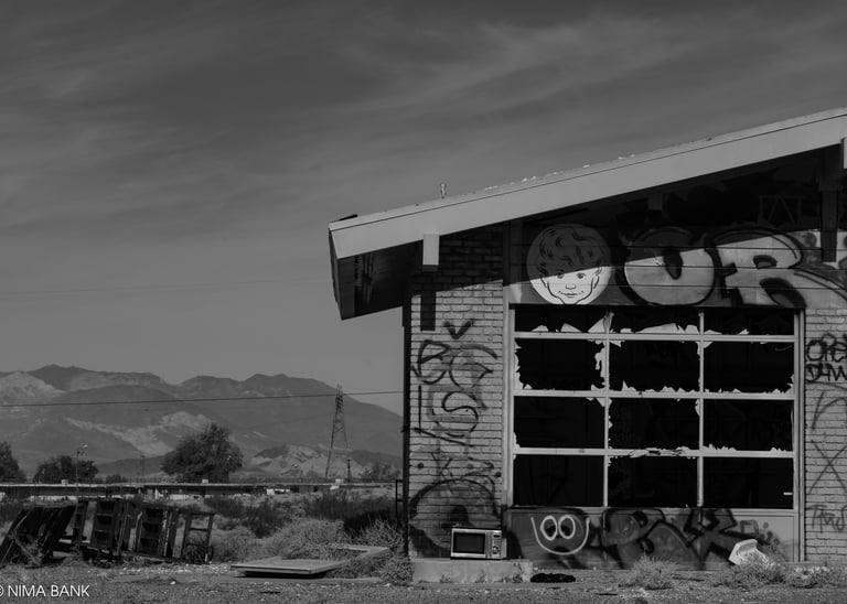 black and white abandoned auto garage with graffiti and mountains in baker california