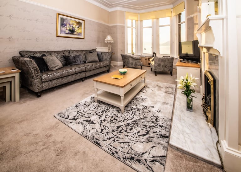 The spacious living room at Gourock Seaview Holiday Let with a couch, armchairs and a fireplace