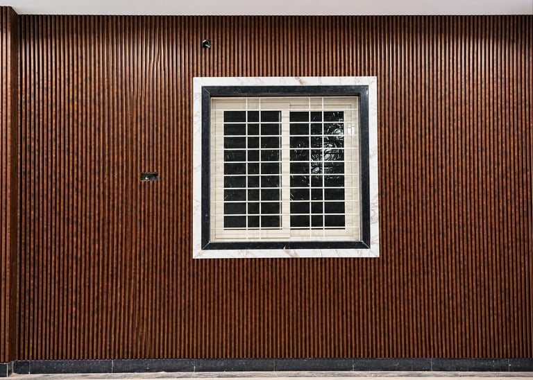 Modern interior wall featuring dark wood fluted panels and a window with a decorative marble frame.