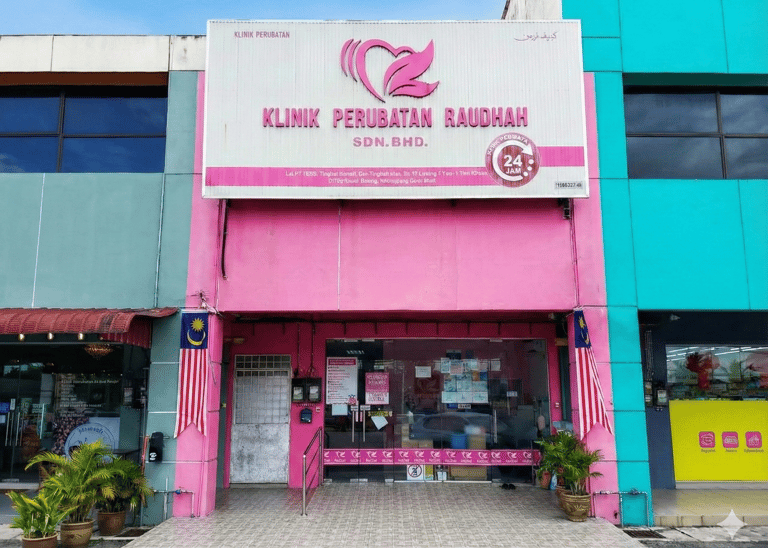 Pink storefront of Klinik Perubatan Raudah, a 24-hour medical clinic in Malaysia with glass doors.