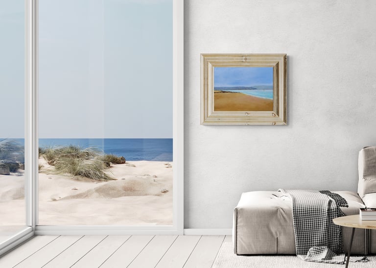 Modern living room with beach wall art and view of sand dunes through a large window.