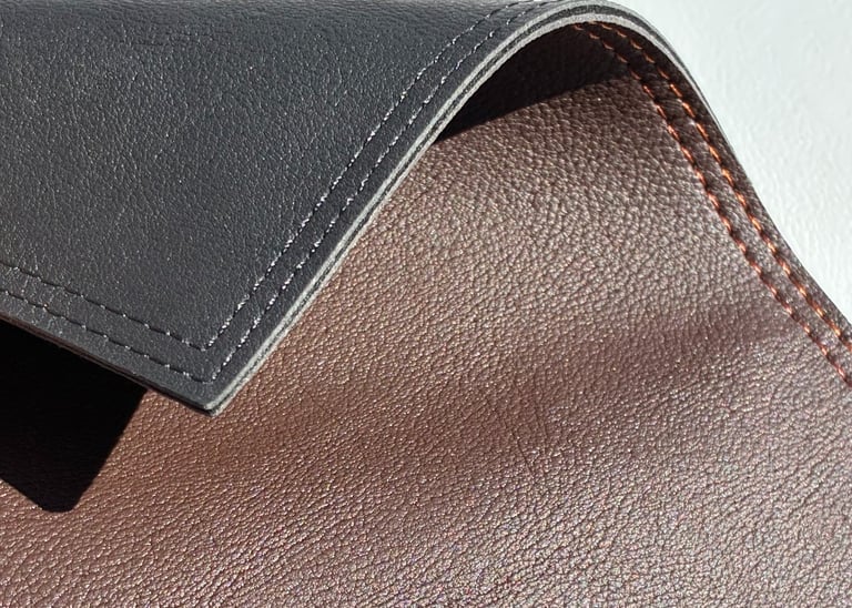 Detalle de un individual de similcuero graneado en color negro y marrón, con finas costuras