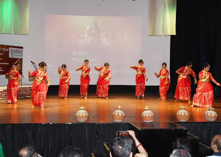 A vibrant group of young girls in traditional kathak attire performing a synchronized dance on stage