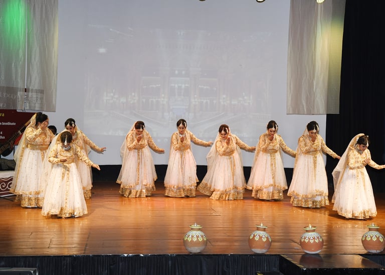 A vibrant group of young girls in traditional kathak attire performing a synchronized dance on stage
