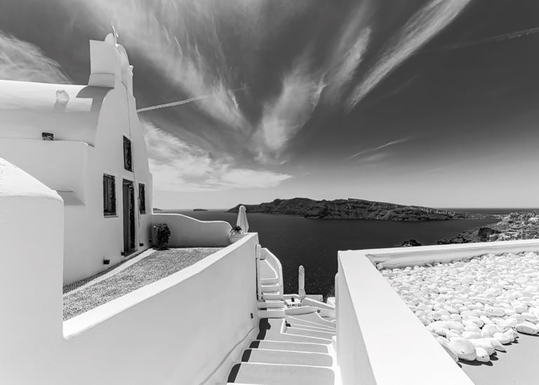 a black and white photo of a house with stairs leading to a balcony