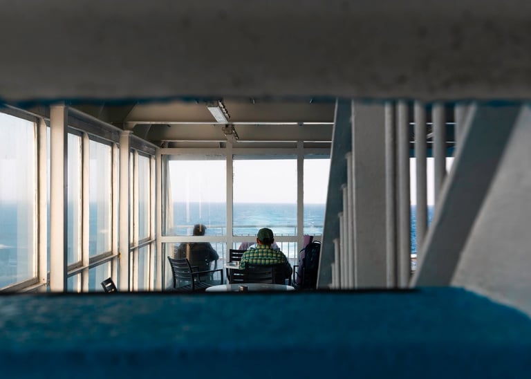 a man and woman sitting at a table with a view of the ocean