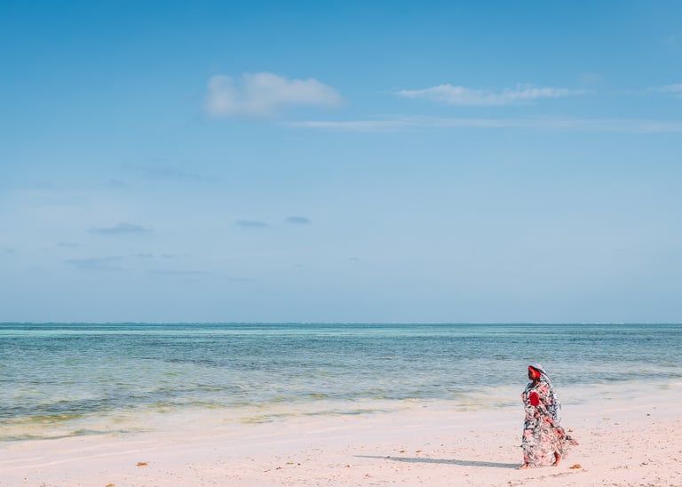 a woman in a red dress walking on a beach of Zanzibar