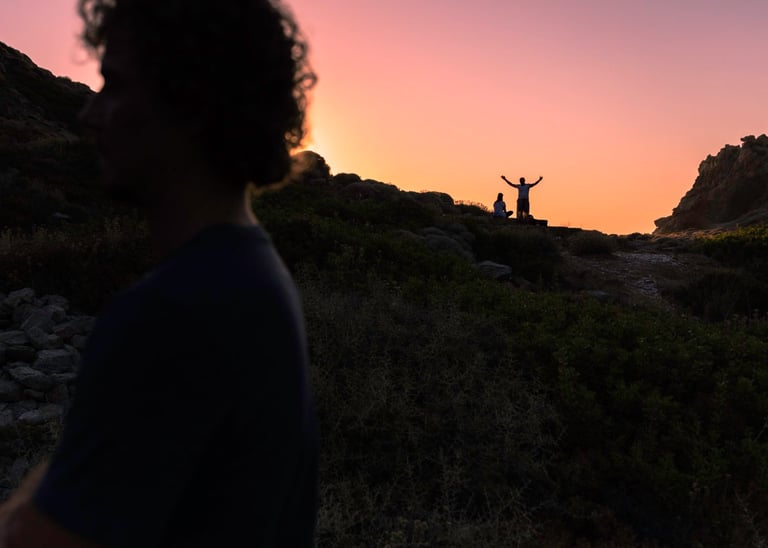 a man standing on a hill with his arms up in the air