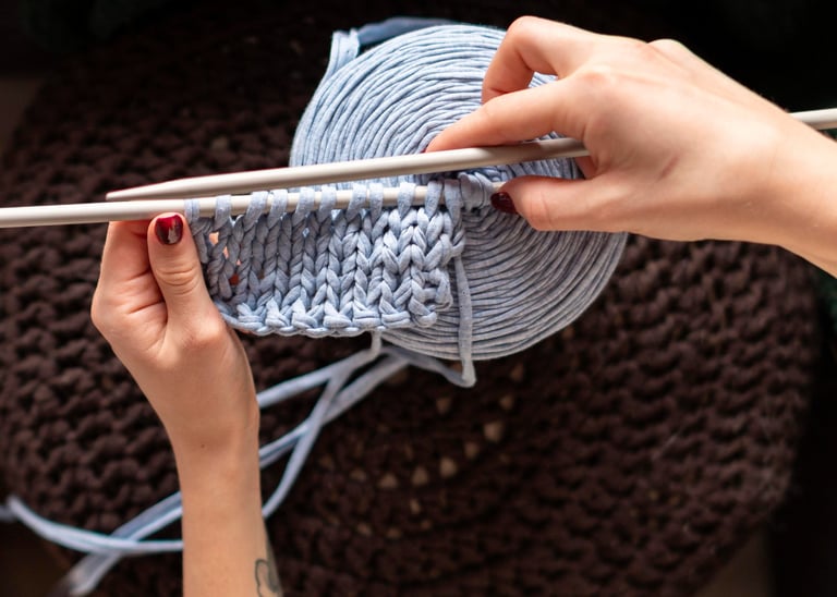 manos tejiendo con agujas un proyecto en trapillo azul