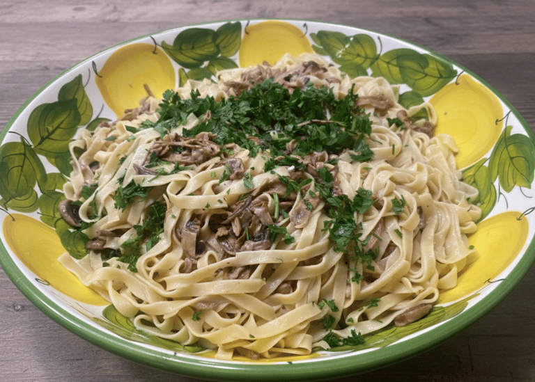 Creamy mushroom fettuccine pasta topped with fresh parsley in a ceramic lemon-patterned bowl.