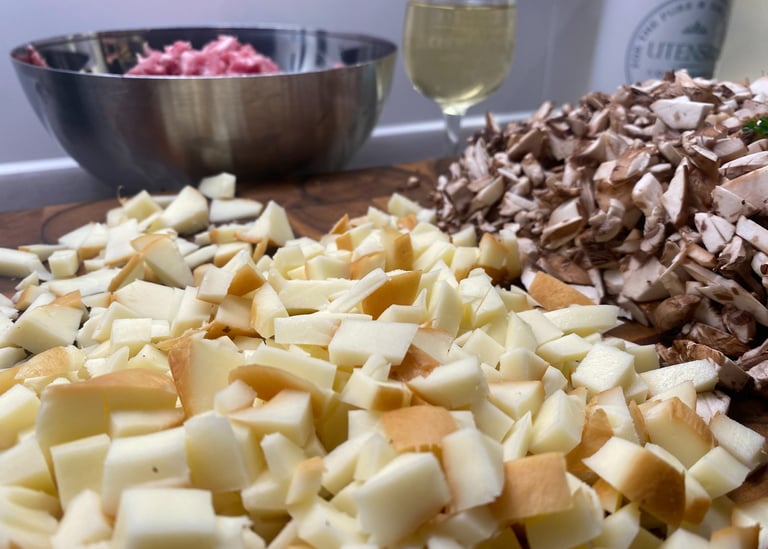 Chopped smoked cheese, sliced mushrooms, and ground meat prepared for cooking on a wooden board.