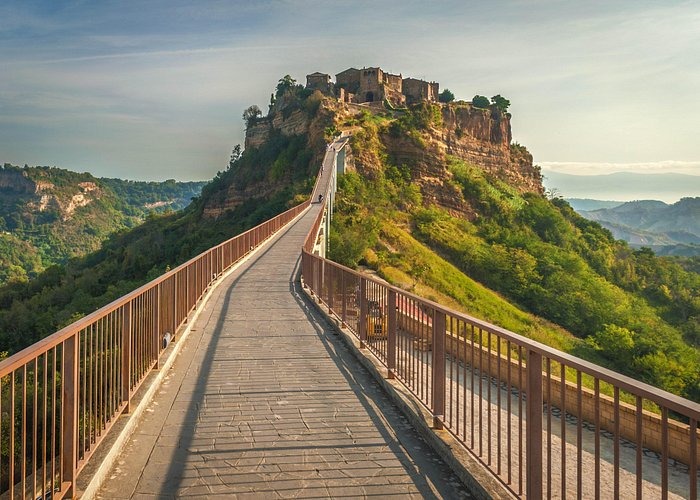 A long stone pedestrian bridge leads to the hilltop village of Civita di Bagnoregio in Italy.