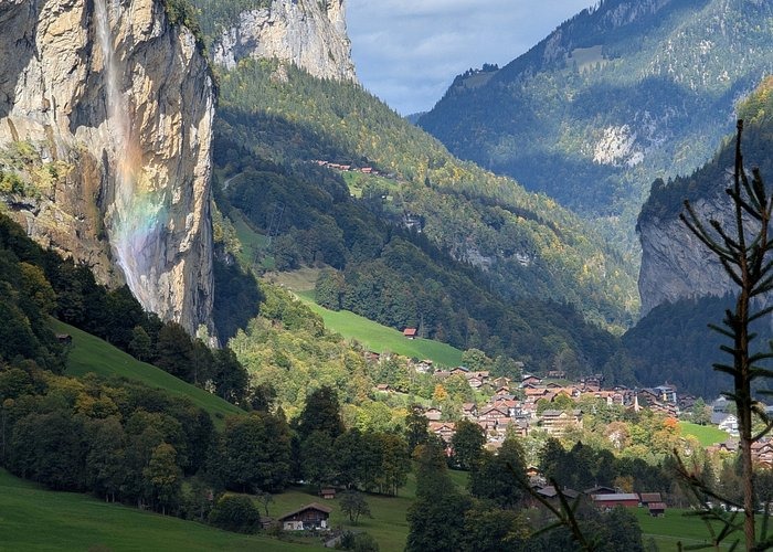 Waterfall with a rainbow falling into the scenic Lauterbrunnen Valley village in the Swiss Alps.