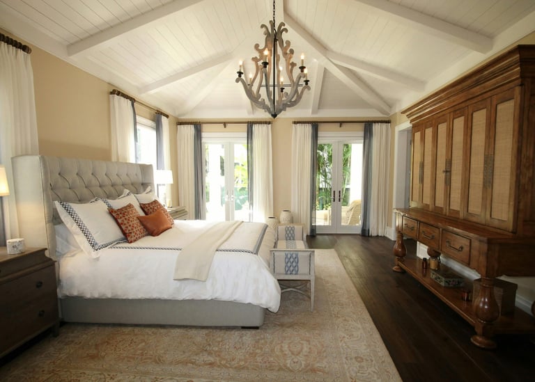 Elegant master bedroom with a vaulted ceiling, wood chandelier, and tufted headboard.