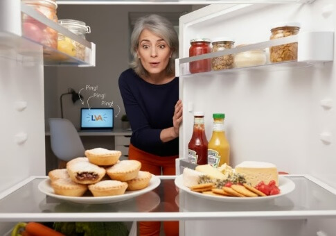 Woman distracted by Christmas food while her laptop pings unanswered in the background.