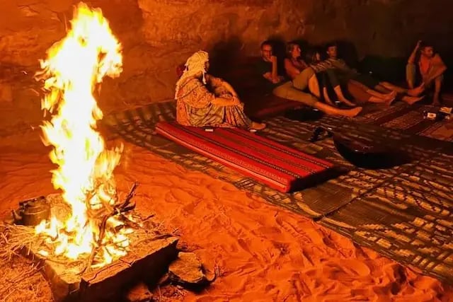 Guests sitting around the fire during bivouac camping in Wadi Rum