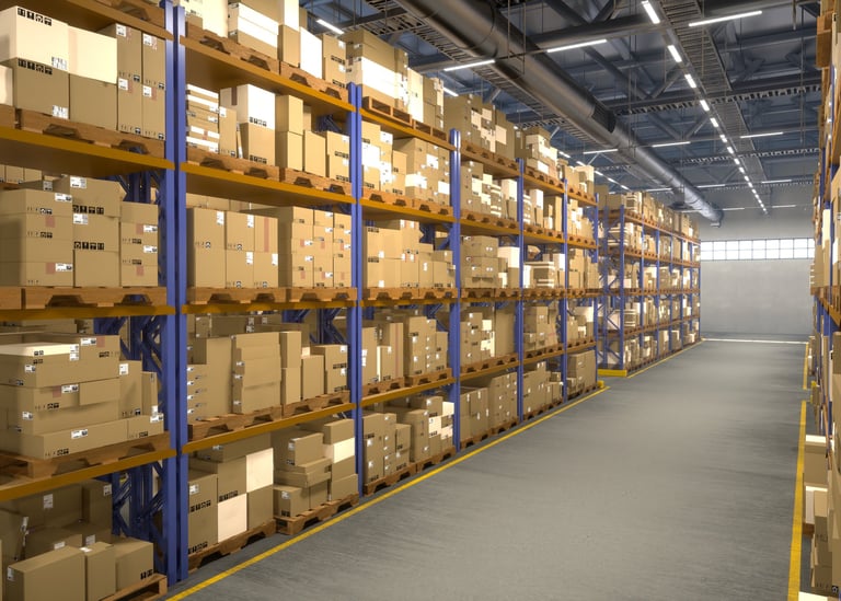 Caixas de papelão empilhadas em paleteiras metálicas industriais em um galpão de distribuição