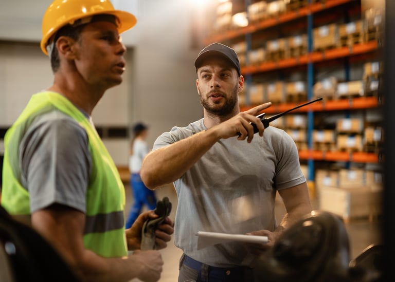 Funcionários de armazém com equipamentos de segurança discutindo gestão logística