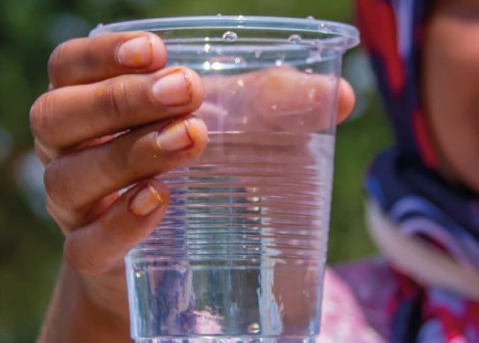 Eine Frau hält einen Becher Wasser