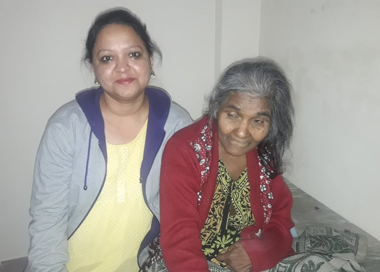 a woman sitting on a bed with an old woman