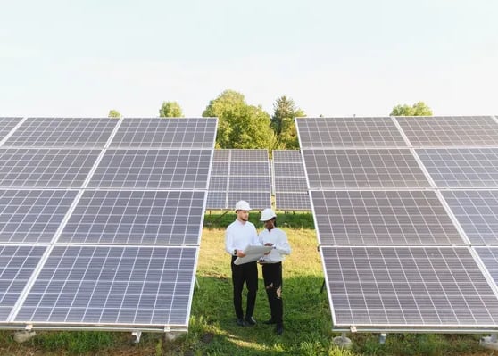 Fotografía de un hombre y una mujer con casco de protección parados en medio de paneles solares en S