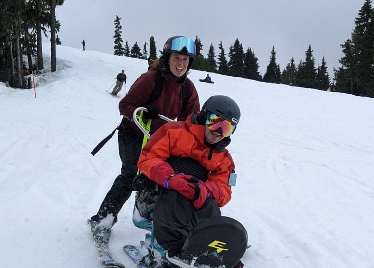 Sean and ski partner Jacqueline skiing towards the camera smiling