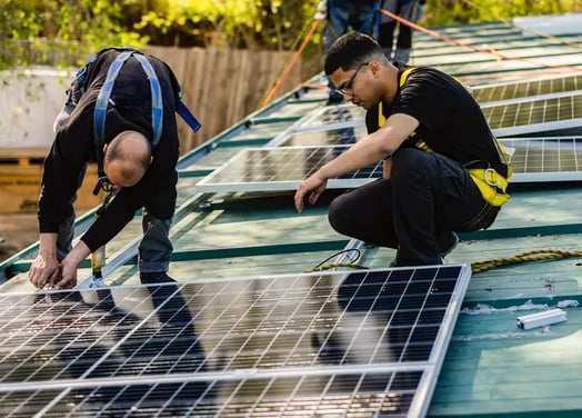 Dos hombres con camisa negra y portando equipos de protección personal trabajando en la instalación