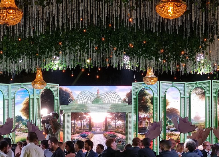 a group of people standing on a stage in front of wide led screen with garden scenery on it