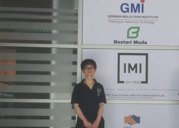 a woman wearing IMI certified shirt infront of window