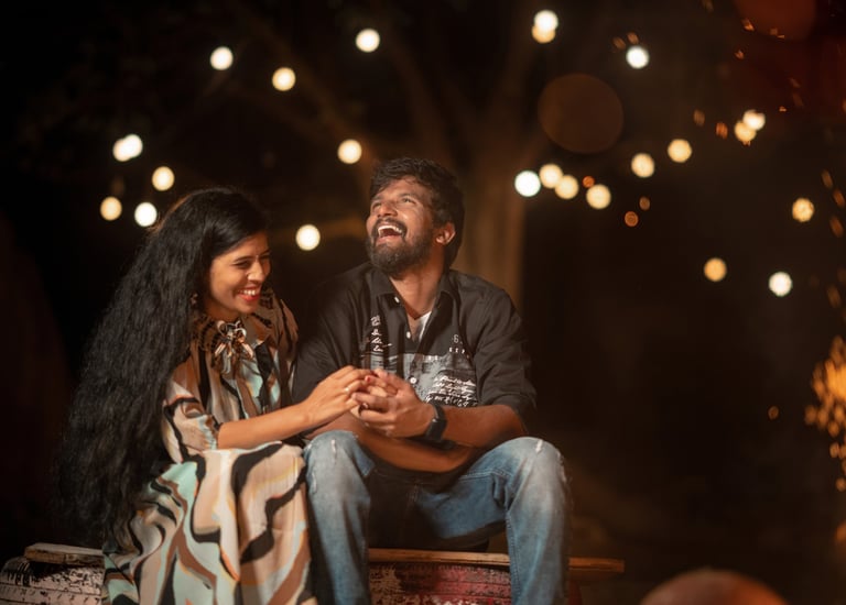 a man and woman sitting on a bench in front of a fire pit